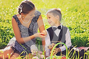 Little boy and teen age girl having picnic outdoors