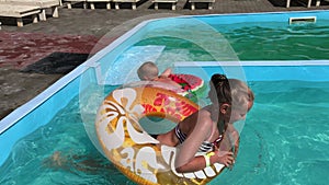 A little boy and a teenage girl frolic in the pool on inflatable circles.
