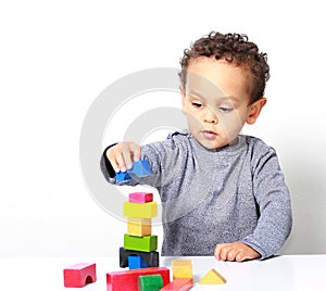 Little boy testing his creativity by building towers with toy building blocks