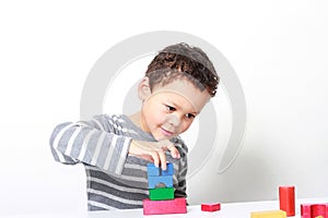 Little boy testing his creativity by building towers with toy building blocks