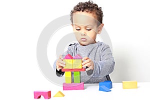 Little boy testing his creativity by building towers with toy building blocks