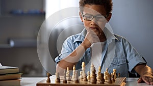 Little boy thinking on chess move, intelligent hobby, logic development, leisure