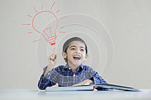 Little boy thinking an idea under a light bulb