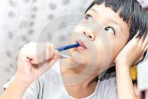 Little boy thinking about somthing and looking up, confused about an idea. Small child hand holding pencil