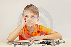 Little boy thinks that assemble from mechanical constructor