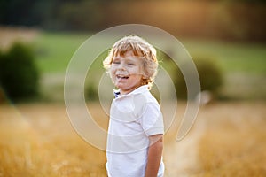 Little boy of three years having fun on yellow hay field