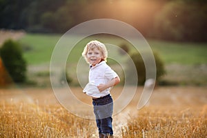Little boy of three years having fun on yellow hay field