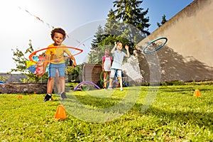 Little boy throw color hula hoop to target cone