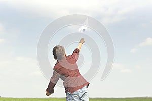 A little boy throwing a paper plane in the sky