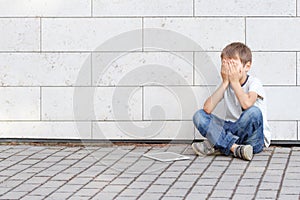 Little boy tired sad and stressed with tablet computer PC. Kid sitting on the ground, holding his head, close eyes