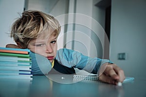 Little boy tired stressed of reading, doing homework