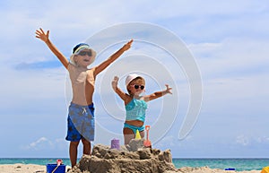 Little boy and toddler girl play with sand on beach