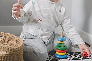 Little boy toddler playing with children multi-colored developing pyramid. Home lifestyle concept