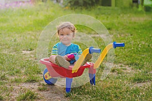 Little boy toddler playing with colorful children's plastic building wheelbarrow