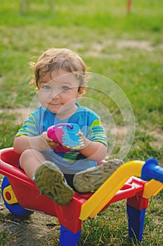 Little boy toddler playing with colorful children's plastic building wheelbarrow