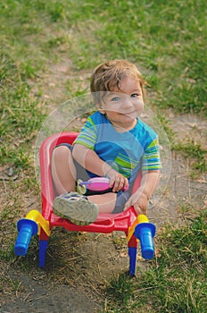 Little boy toddler playing with colorful children's plastic building wheelbarrow