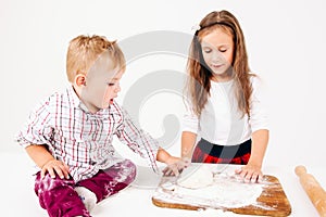 Little boy touching raw dough near sister