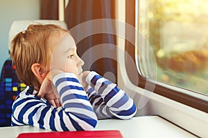 Little boy is traveling on the train. Kid travels on a train. Cute child looking out the train window