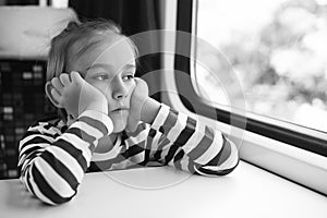 Little boy is traveling on the train. Kid travels on a train. Cute child looking out the train window