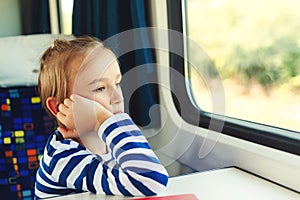 Little boy is traveling on the train. Kid travels on a train. Cute child looking out the train window