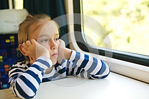 Little boy is traveling on the train. Kid travels on a train. Cute child looking out the train window