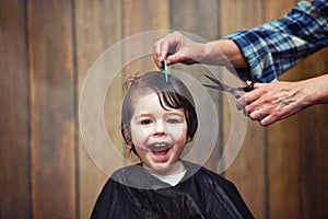 A little boy is trimmed in the hairdresser`s