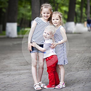 Little boy and two older cousins, meeting in the summer park