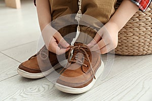 Little boy tying shoe laces at home, closeup