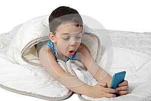 Little boy under blanket look astonished to smart phone