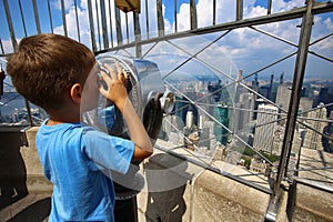 Little boy using binoculars and watched on the New York Skyline