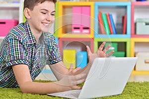 Little boy using laptop while lying on floor