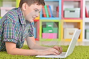 Little boy using laptop while lying on floor