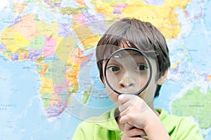 Little boy using magnify looking on map