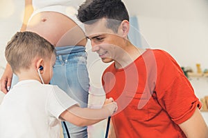 little boy using a stethoscope to listen to the heartbeat of his dad