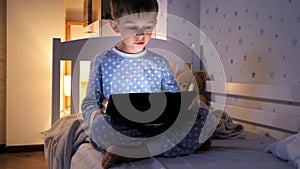 Little boy using tablet computer in his bedroom at night. Children education, development, kids using gadgets secrecy, privacy