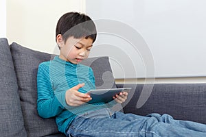 Little boy using tablet and sitting on sofa