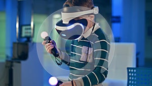 Little boy in virtual reality headset holding move motion controllers