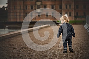 Little boy is walking on a dirt road to an old building