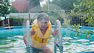 A little boy walking out of an inflatable swimming pool