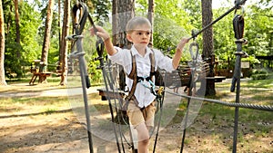 Little boy walking over rope bridge at outdoor amusement park. Active childhood, healthy lifestyle, kids playing outdoors,