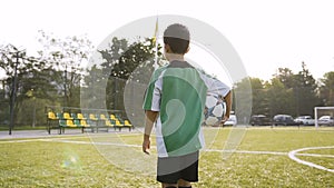 Little boy walking with soccer ball in the hand.