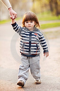 Little boy walking on spring day holding hand of his mother