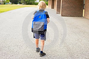 Little boy walking to school, carrying backpack. Back to school concept photo