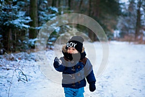 Little boy walking in the winter forest