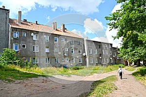 A little boy walks along a path past old residential buildings. Sovetsk, Kaliningrad region