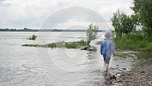 Little boy walks along the river. the child runs around the lake. slow motion. happy baby playing near the water.