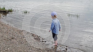 Little boy walks along the river. the child runs around the lake. slow motion. happy baby playing near the water.