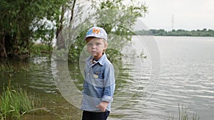 Little boy walks along the river. the child runs around the lake. slow motion. happy baby playing near the water.