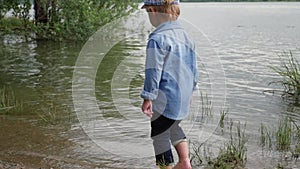 Little boy walks along the river. the child runs around the lake. slow motion. happy baby playing near the water.