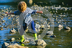 A little boy walks near the lake or river. Little boy playing near river in sunny day. Happy childhood and children